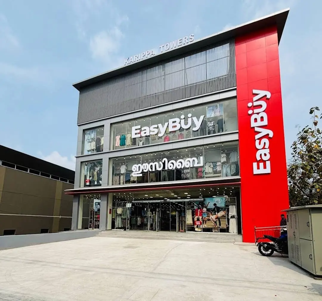 Three-storey retail building with a red ACP fin, grey cladding and a glass shopfront